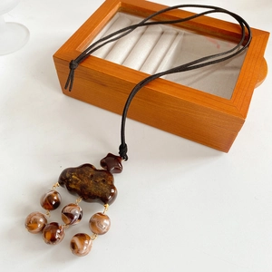 Detail of dark brown cloud pendant with star detail and round bead on black necklace cord