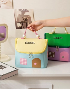 Dettaglio della borsa da trucco a forma di casa con manico di perle e colori macaron