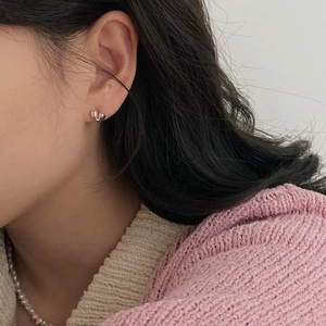 Close-up of minimalist silver heart stud earring worn by model for elegant style