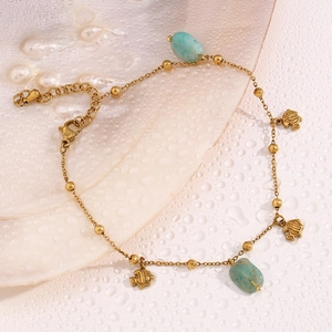 Macro detail of 18K gold-plated fish charm anklet with light blue amazonite beads