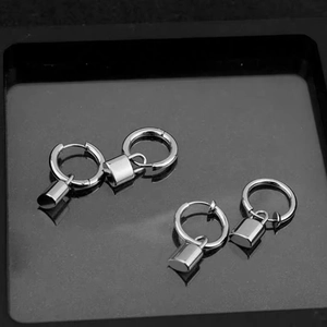 Punk silver padlock earrings and minimalist steel hoops set on black reflective surface