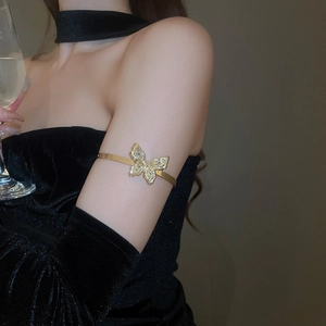 Detailed close-up of a sparkling gold butterfly arm cuff with inlaid crystals on a model