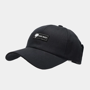 Detail of black baseball cap featuring a hand made patch with a white tree icon