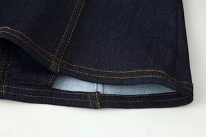 Vue macro détaillée du tissu denim bleu foncé avec doubles coutures orange contrastées
