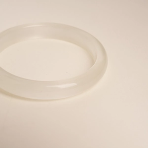 Close-up of a white translucent cat's eye stone bangle with smooth polished finish