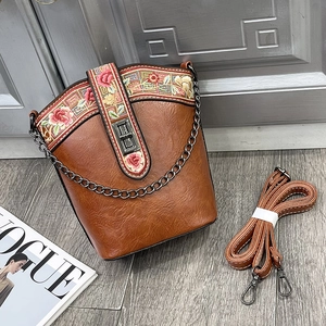 Detailed embroidery and leather texture on a vintage brown crossbody bucket bag