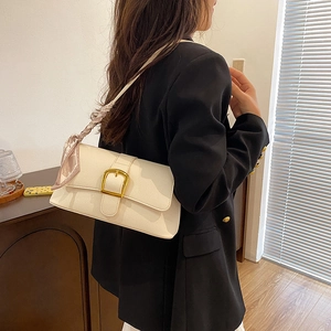 Detail of cream shoulder bag featuring gold square buckle and decorative floral silk scarf