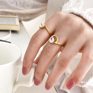 Adjustable gold ring with double pear-shaped zircons on a model's hand with coffee background