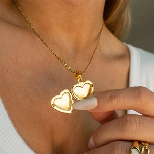 Model wearing a gold heart locket pendant necklace with an openable photo compartment