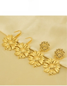 Detailed view of golden sunflower earrings in durable stainless steel on silk background