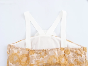 Detail aus goldenem Jacquard-Stoff mit 3D-Blumenmuster und weißen Kreuzträgern