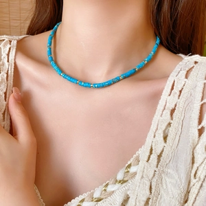 Close-up of blue stone bead necklace with gold spacers worn on neck for a minimalist look