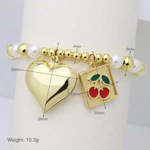 Macro shot showing dimensions of gold heart and cherry charms on a beaded bracelet