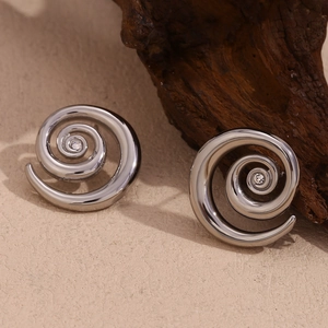 Detailed macro view of spiral silver stud earrings with zircon stones on wooden background