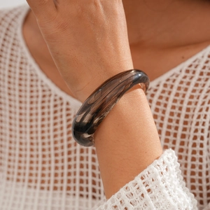 Macro shot of minimalist smoky acrylic round bracelet on a model's wrist with detail
