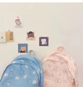 Detail showing blue and pink canvas backpacks with cute cartoon bear and cloud patterns