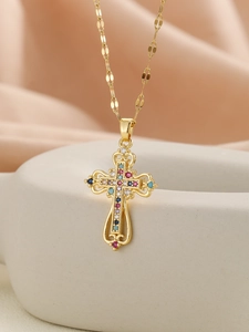 Detail of gold cross necklace with colorful zircons hanging on a grey ceramic bowl