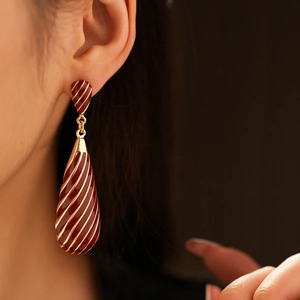 Gros plan sur boucle d'oreille goutte vintage émail bordeaux et rayures dorées