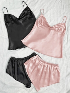 Ensemble pyjama en satin avec caraco et short en rose et noir sur fond de tissu