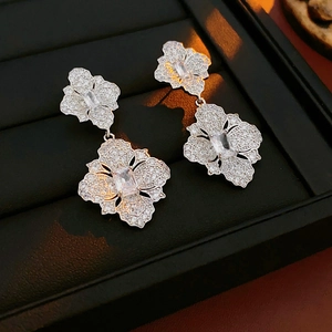 Détail de boucles d'oreilles fleur en argent avec zircons sur un support de présentation noir