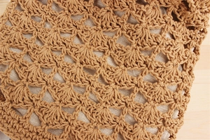 Macro shot of khaki crochet cotton rope woven bag with intricate floral cut-out details