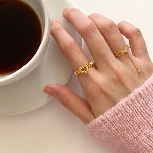 Detail of adjustable gold heart ring and tassel chain ring on a female hand