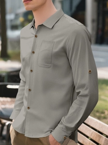 Detail of grey linen shirt showing chest pocket and sleeve button on male model outdoors