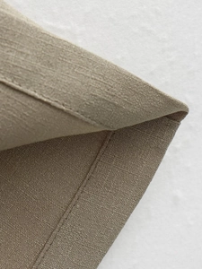 Detailed macro view of khaki linen blend fabric texture and professional stitching seams