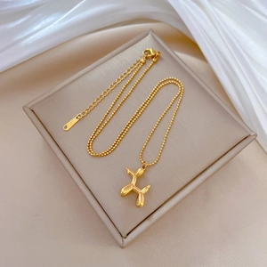 Titanium steel balloon dog pendant necklace in 18k gold plating on silk background
