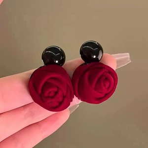 Dettaglio macro di orecchini a petalo di rosa rossa floccata con perno sferico nero