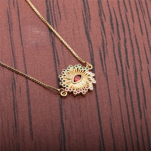 Collier pendentif œil maléfique doré avec zircon rouge sur fond bois sombre