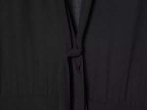 Detailansicht des Knotendesigns am schwarzen Kleid mit feiner gewebter Stoffstruktur