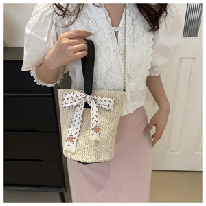 Gros plan détaillé d'un sac seau en paille beige avec un foulard en soie à motifs chic