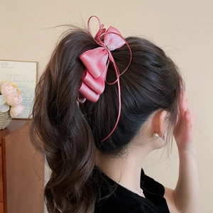 Detail of pink satin bow hair clip with pearl decor on high ponytail hairstyle