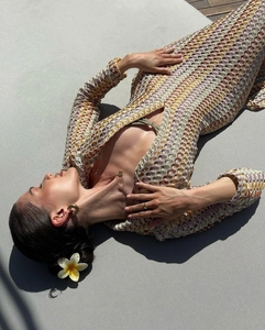 Detailed macro view of bohemian crochet knit texture on a long sleeve V-neck beach maxi dress