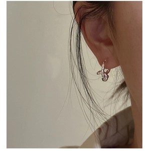 Close-up of a model wearing a silver knotted earring with liquid metal texture finish