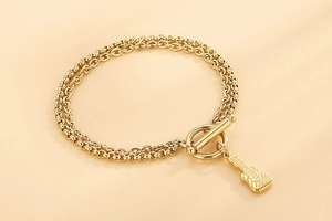 Detaillierte Makroansicht der goldenen Doppelketten-Armband mit Gitarrenanhänger und OT-Verschluss