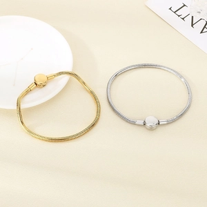 Close-up of gold and silver crown heart charm snake bone bracelets on a ceramic plate