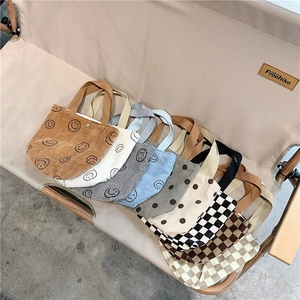 Corduroy tote bags collection with smiley face and checkerboard patterns on a chair