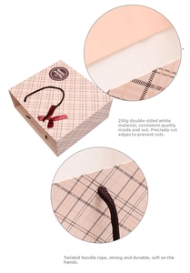 Detail of 250g pink plaid gift bag featuring braided handles and a red bow decoration