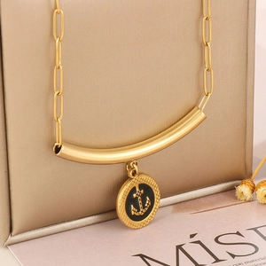 Macro view of gold-tone paperclip chain necklace with a black enamel anchor pendant