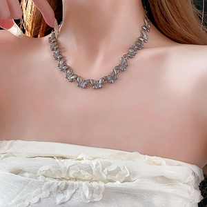 Close-up of a silver butterfly choker necklace worn by a model to show intricate details