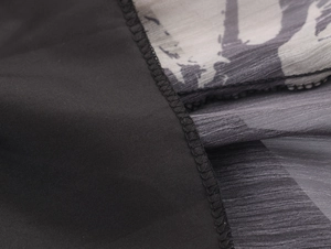 Detailed close-up of brushstroke print chiffon fabric and stitching on elegant black dress