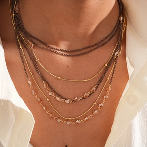 Detail of multi-layer gold necklace with champagne crystals and woven dark chains