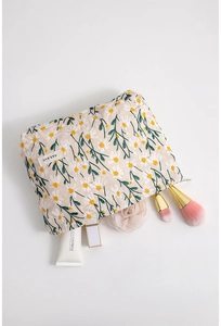 Detailaufnahme der beigen Baumwoll-Kosmetiktasche mit weißer Gänseblümchen-Stickerei