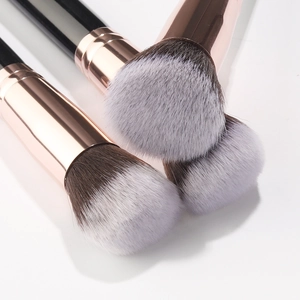 Close-up of three soft makeup brushes with rose gold ferrules and dense synthetic bristles