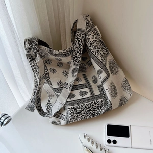 Close-up of beige cotton linen canvas bag with black paisley print and wide shoulder strap