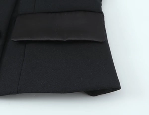 Dettaglio della trama del tessuto nero e cuciture della tasca a patta sulla giacca blazer