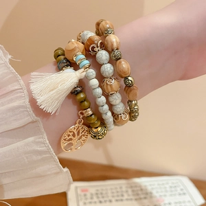 Detail of layered bohemian sandalwood bracelet with tassel and tree of life charm