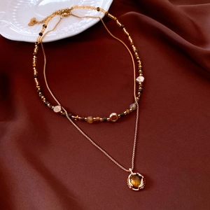 Détail du collier double couche plaqué or 18 carats avec perles œil de tigre sur soie